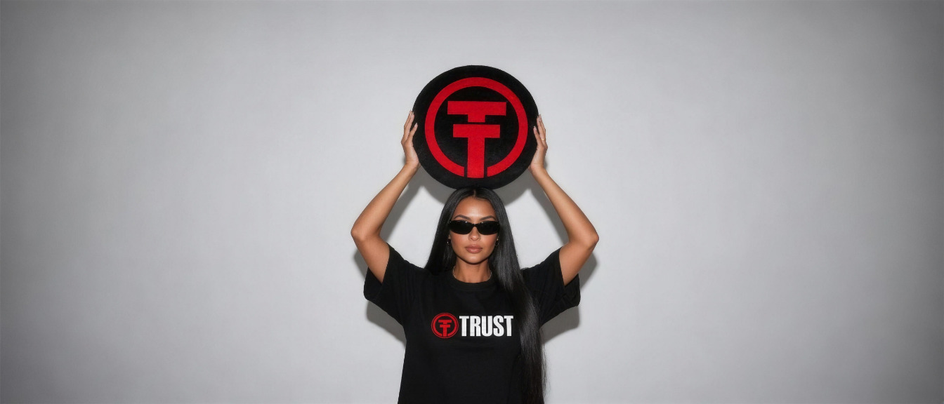 Modelo de óculos escuros e camiseta Trust levantando uma almofada com o símbolo da Trust